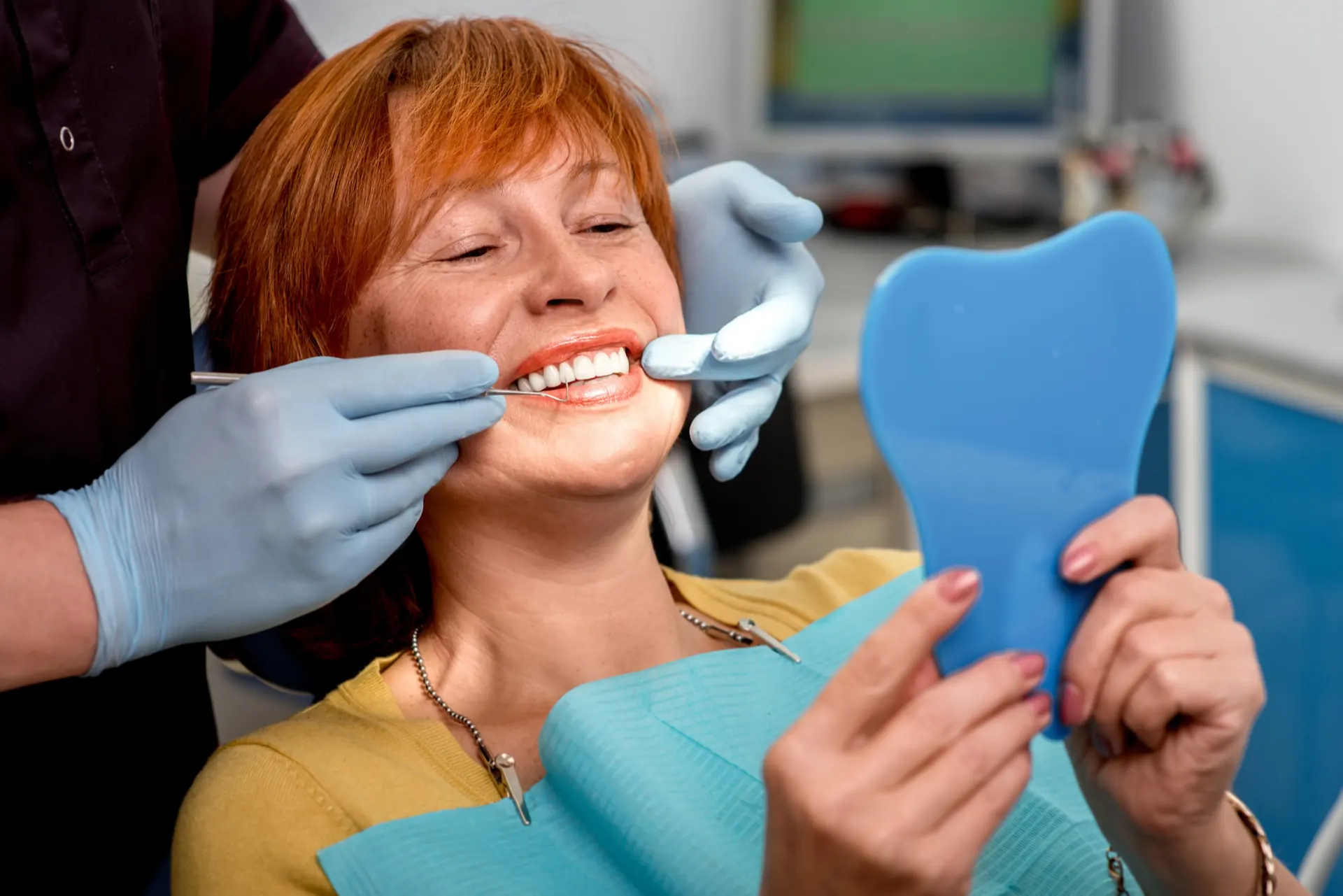 Older patient smiling in a dental chair after implant treatment